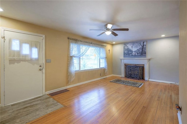 unfurnished living room with baseboards, a fireplace, visible vents, and hardwood / wood-style floors