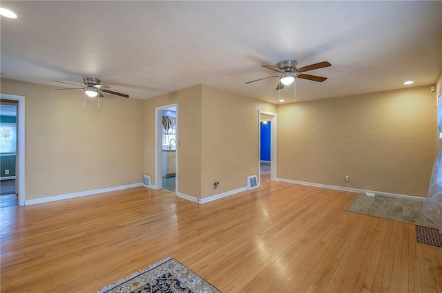 unfurnished living room with light wood finished floors, a ceiling fan, visible vents, and baseboards