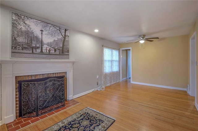 living room with recessed lighting, a tiled fireplace, wood finished floors, and baseboards