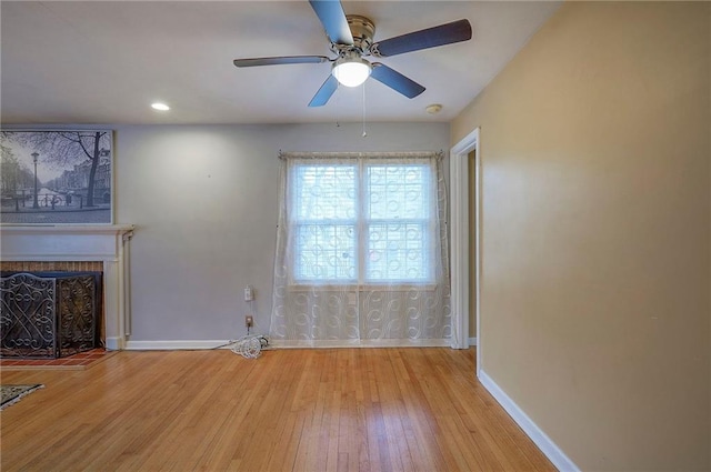 unfurnished living room featuring hardwood / wood-style flooring, ceiling fan, a fireplace, and baseboards