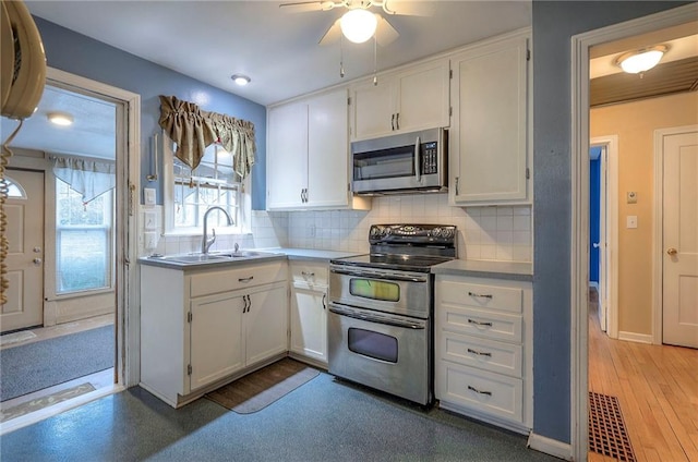 kitchen featuring decorative backsplash, white cabinetry, stainless steel appliances, and a sink