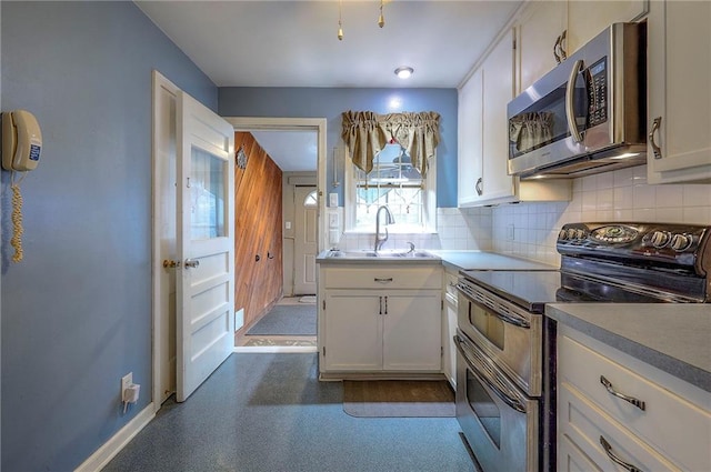 kitchen with white cabinetry, appliances with stainless steel finishes, decorative backsplash, and a sink