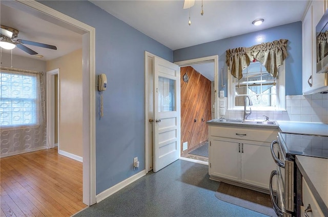 kitchen with stainless steel appliances, backsplash, a ceiling fan, white cabinetry, and a sink