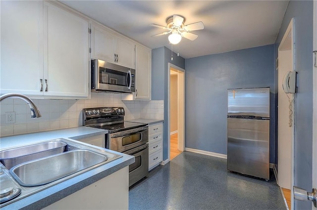 kitchen featuring tasteful backsplash, baseboards, white cabinets, stainless steel appliances, and a sink