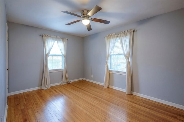 spare room featuring a healthy amount of sunlight, light wood-type flooring, and baseboards