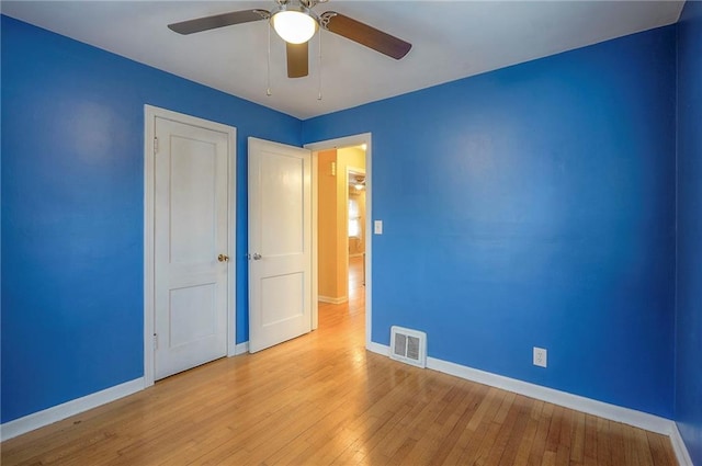 spare room featuring ceiling fan, wood-type flooring, visible vents, and baseboards