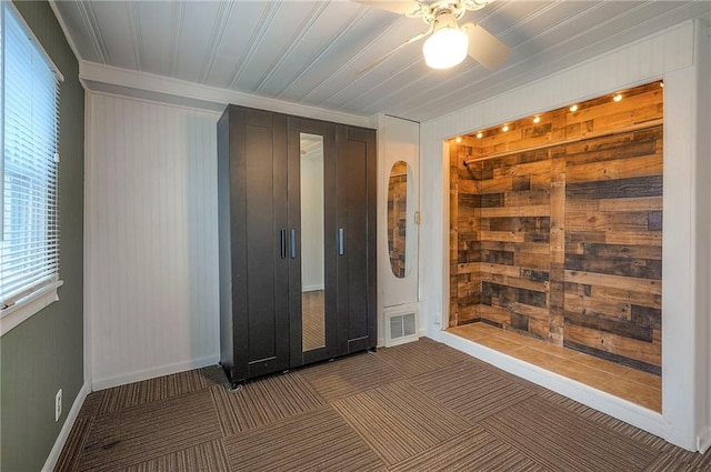 unfurnished bedroom featuring carpet floors, visible vents, wood walls, and baseboards