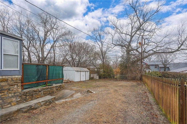 view of yard with a storage unit, an outdoor structure, and fence