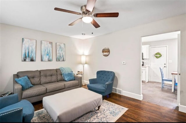 living room featuring a ceiling fan, baseboards, and wood finished floors