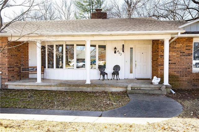 entrance to property featuring a porch, a chimney, board and batten siding, and roof with shingles