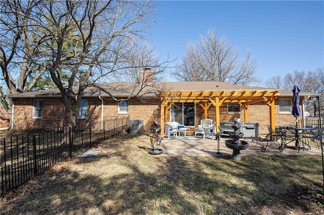 rear view of house featuring brick siding, a pergola, a patio, and fence