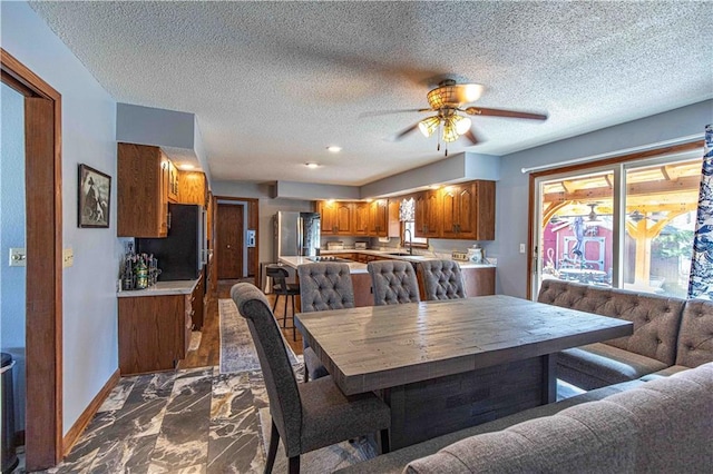 dining area featuring baseboards, a textured ceiling, marble finish floor, and a ceiling fan