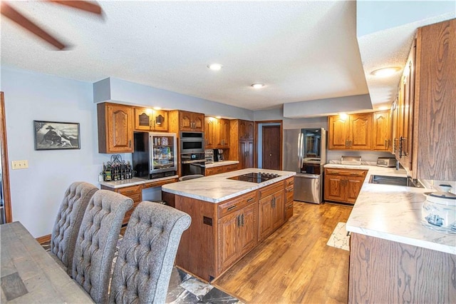 kitchen with light countertops, a center island, brown cabinets, and stainless steel appliances