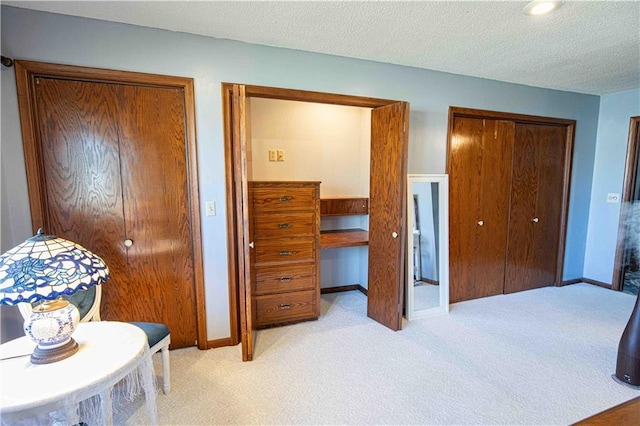 bedroom with a textured ceiling, baseboards, and light carpet