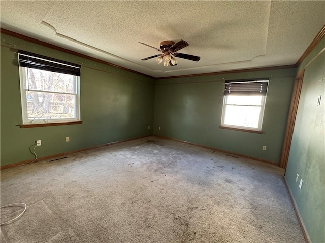 spare room featuring baseboards, ceiling fan, a textured ceiling, crown molding, and carpet floors