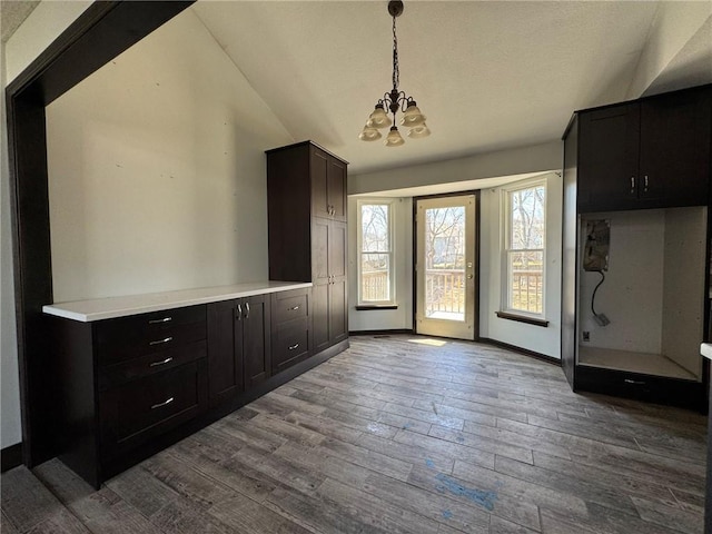 interior space with lofted ceiling, a notable chandelier, baseboards, and dark wood-type flooring