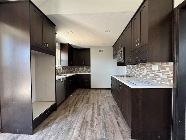 kitchen featuring dark brown cabinetry, visible vents, appliances with stainless steel finishes, light wood-type flooring, and a sink