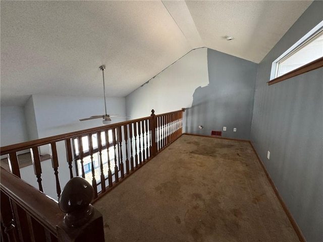 corridor with baseboards, visible vents, vaulted ceiling, a textured ceiling, and carpet flooring