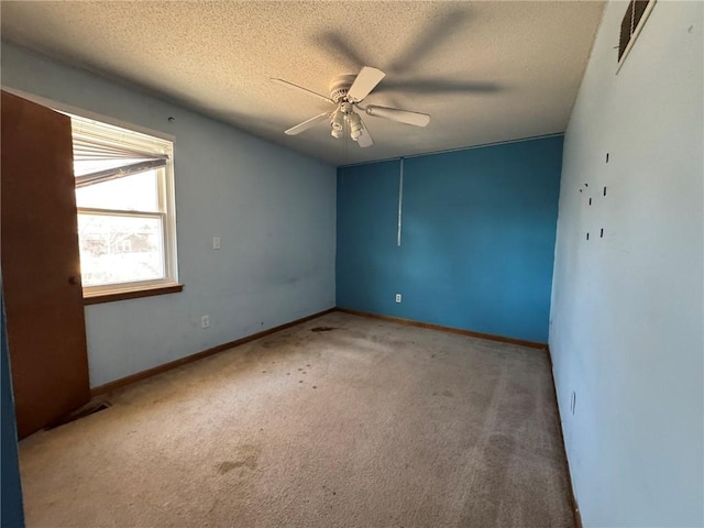 unfurnished room with a textured ceiling, visible vents, carpet flooring, and a ceiling fan