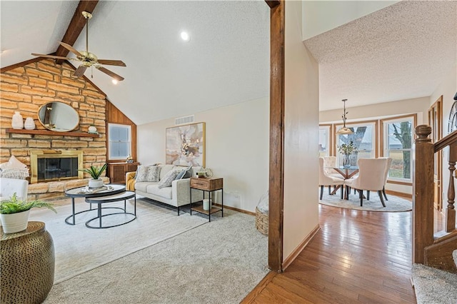 living room featuring visible vents, lofted ceiling with beams, wood-type flooring, a textured ceiling, and a fireplace