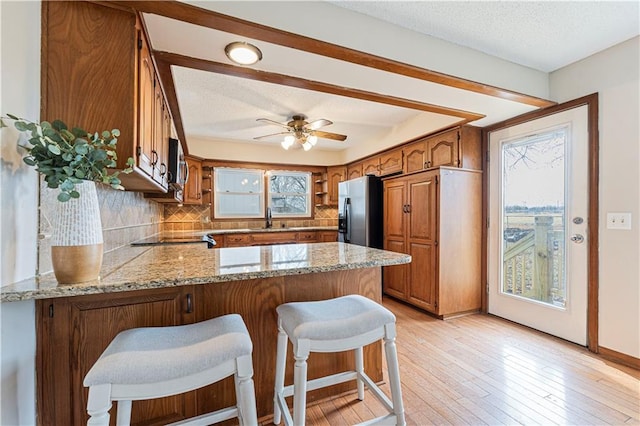 kitchen with stainless steel appliances, backsplash, brown cabinets, and a peninsula