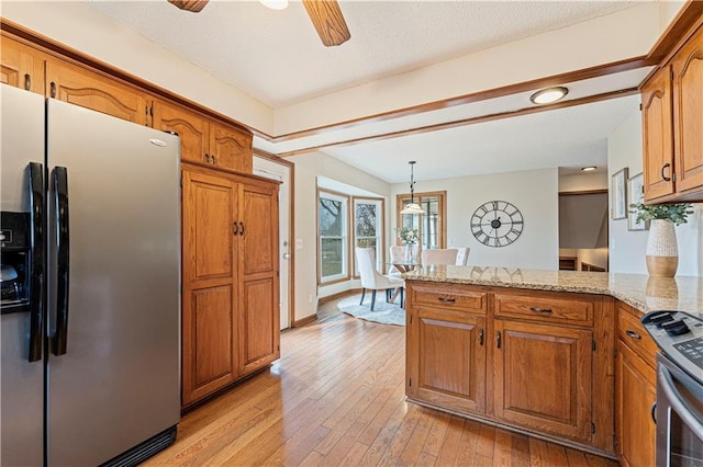 kitchen with brown cabinets, light wood-style floors, a peninsula, and stainless steel appliances