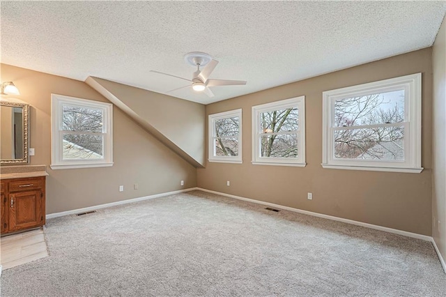 bonus room featuring visible vents, plenty of natural light, light carpet, and a textured ceiling