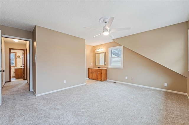 unfurnished bedroom with light carpet, a textured ceiling, and baseboards