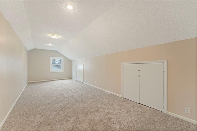 bonus room with lofted ceiling, carpet floors, a textured ceiling, and baseboards