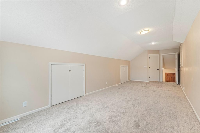 additional living space featuring lofted ceiling, carpet floors, a textured ceiling, and baseboards