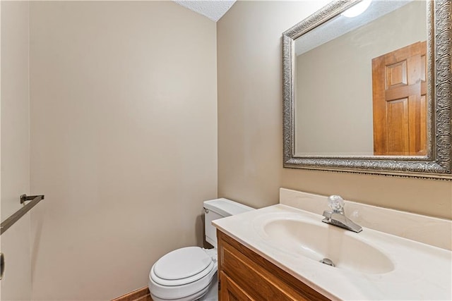 bathroom featuring a textured ceiling, vanity, and toilet