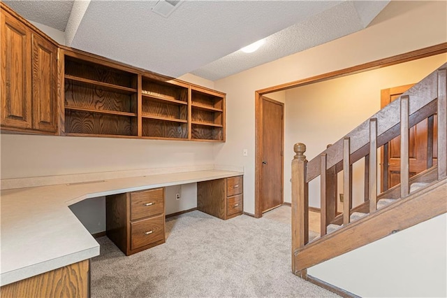 home office featuring light colored carpet, visible vents, built in study area, a textured ceiling, and baseboards