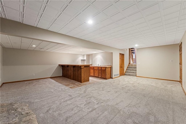 interior space with light carpet, wet bar, stairs, and baseboards