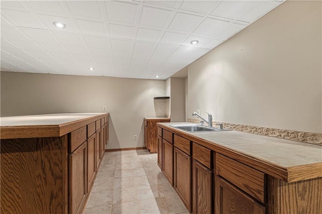 interior space with recessed lighting, brown cabinets, a sink, and baseboards