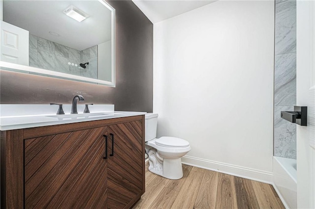 full bathroom with toilet, baseboards, wood finished floors, and vanity