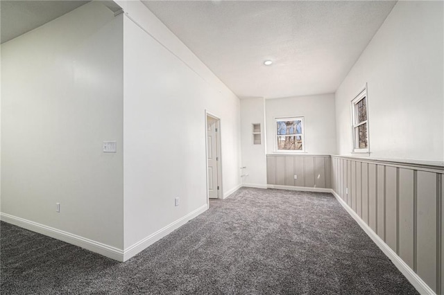 carpeted spare room featuring baseboards and a textured ceiling