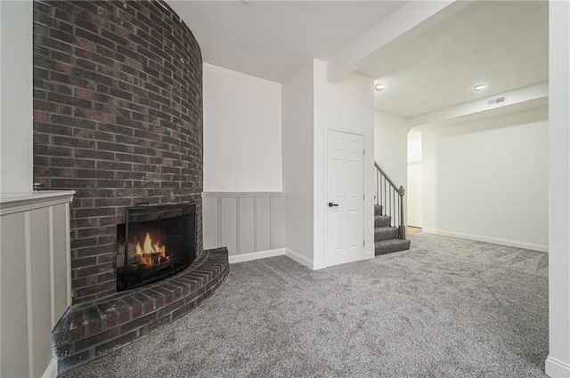 unfurnished living room featuring visible vents, baseboards, stairs, carpet floors, and a fireplace