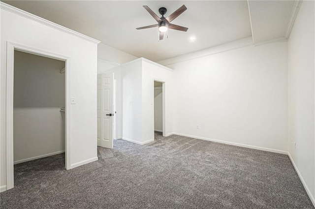 unfurnished bedroom with carpet floors, baseboards, a walk in closet, and ornamental molding