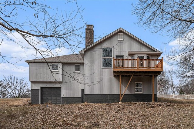 rear view of property with a garage, a chimney, and a wooden deck