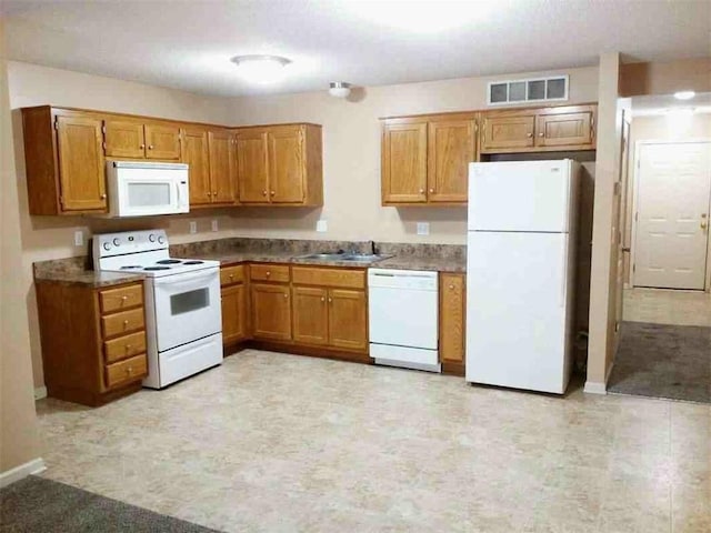 kitchen with white appliances, brown cabinets, visible vents, and a sink