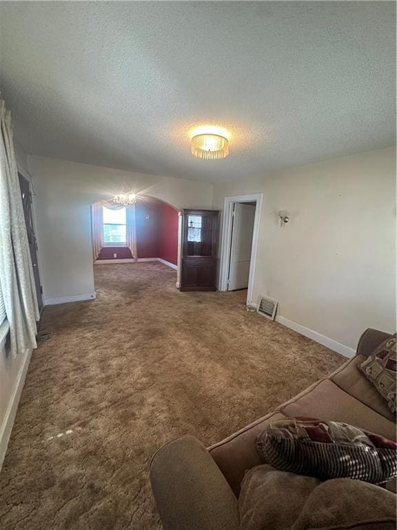 carpeted living room featuring a textured ceiling, arched walkways, visible vents, and baseboards