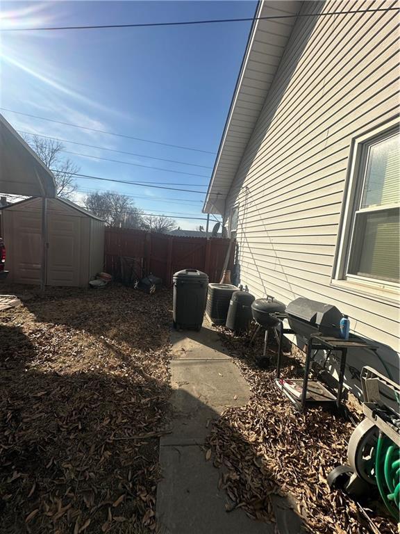 view of home's exterior with a storage shed, central AC, an outdoor structure, and fence