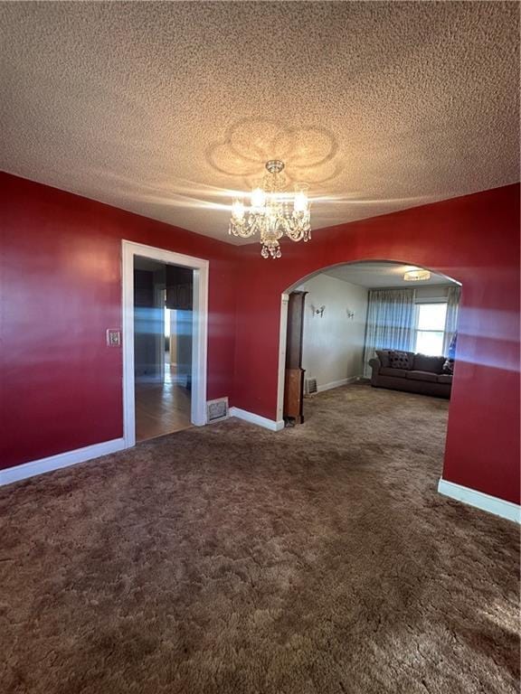 unfurnished room with arched walkways, carpet floors, a textured ceiling, and an inviting chandelier