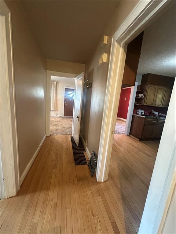 corridor featuring light wood-style flooring and baseboards