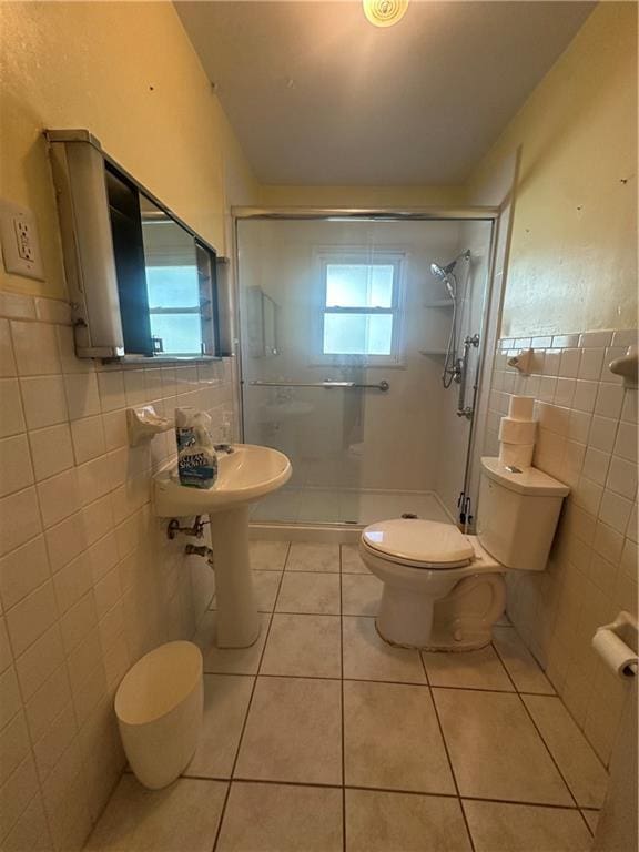 full bathroom with wainscoting, toilet, tile patterned floors, a shower stall, and tile walls