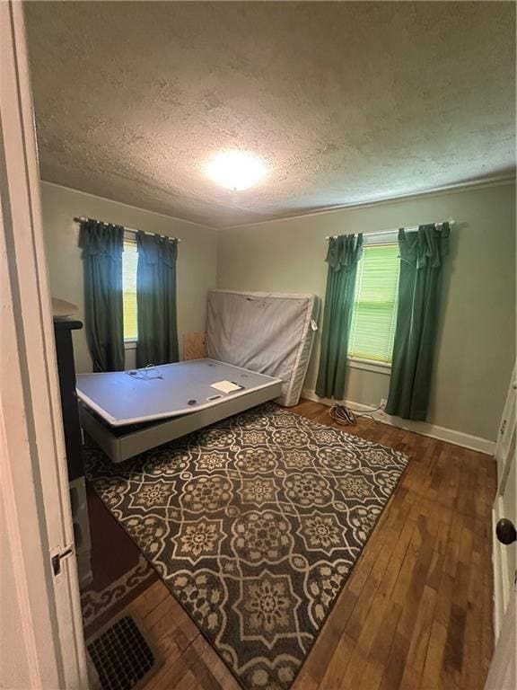 bedroom featuring a textured ceiling, baseboards, and hardwood / wood-style floors