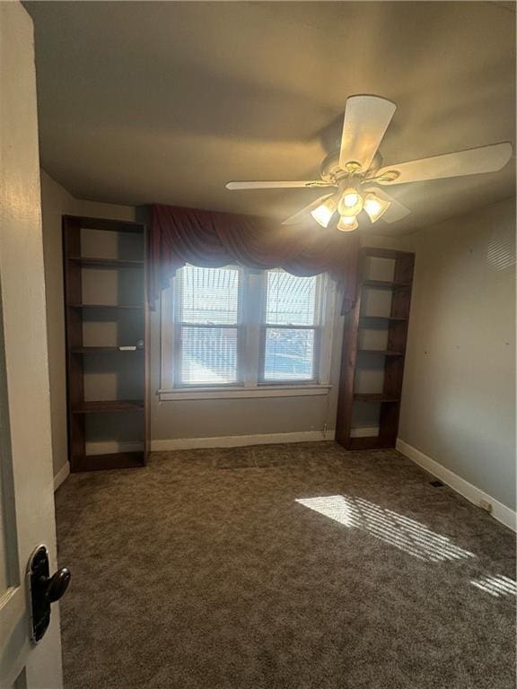 carpeted spare room with ceiling fan and baseboards