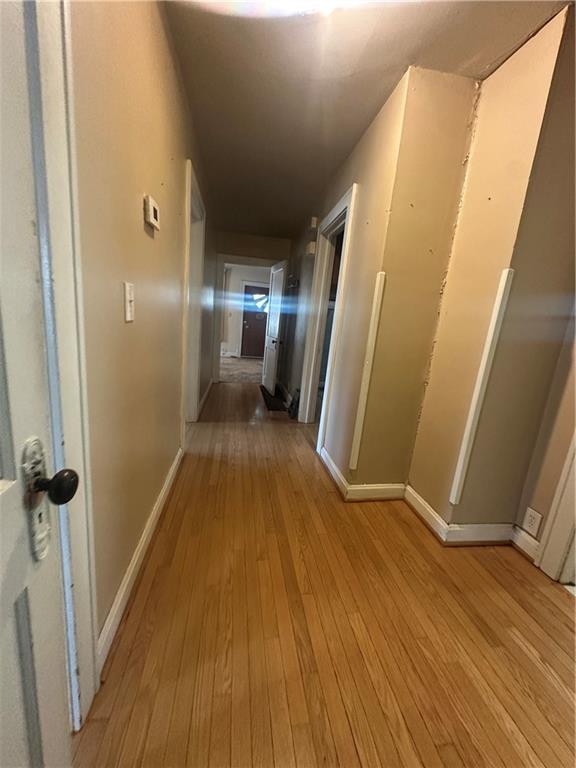 corridor with baseboards and light wood finished floors