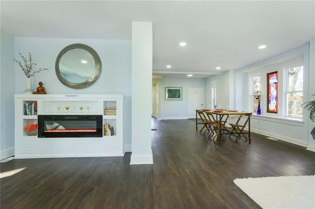 living room featuring recessed lighting, baseboards, wood finished floors, and a glass covered fireplace