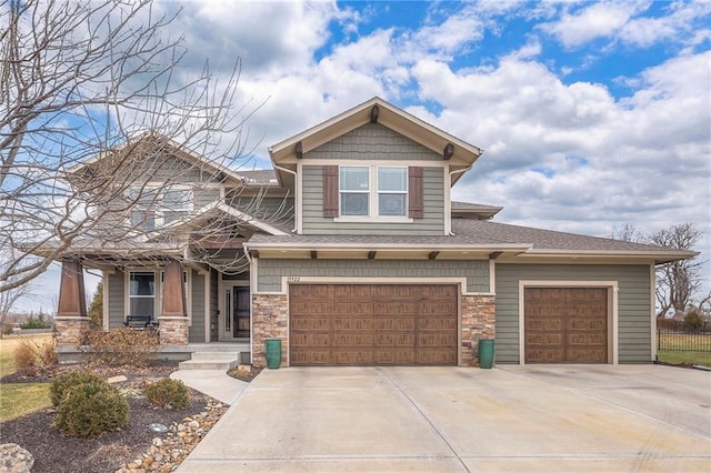 craftsman inspired home with a garage, concrete driveway, stone siding, roof with shingles, and a porch